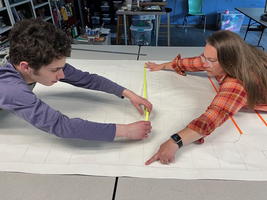 Chayton Martinez and WSA art teacher Sara Adams plot out the sections for the artwork