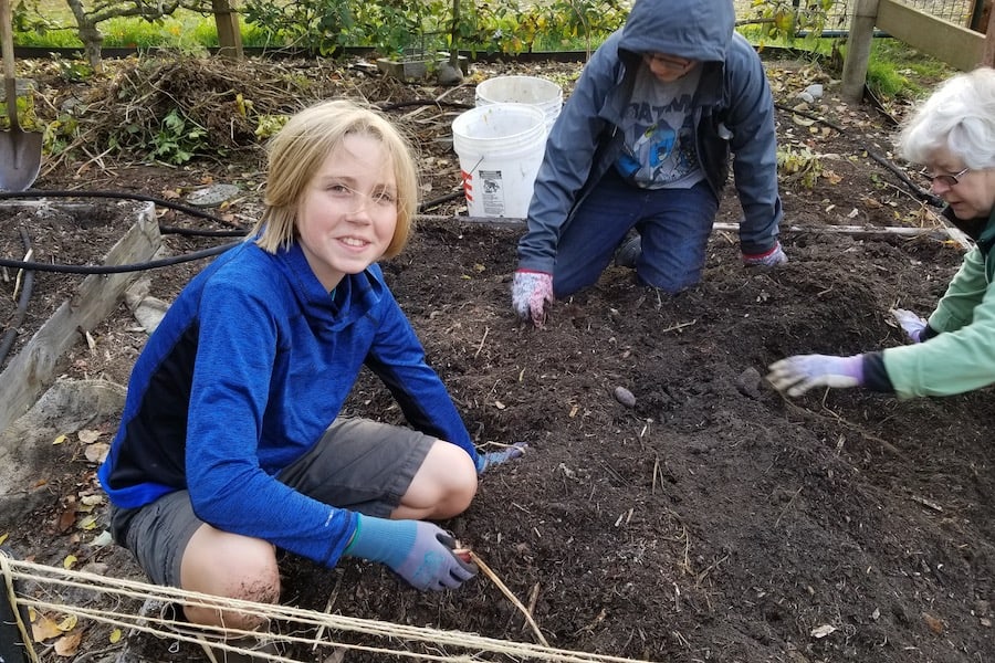 Two Middle School boys work in the Raab Park garden bed