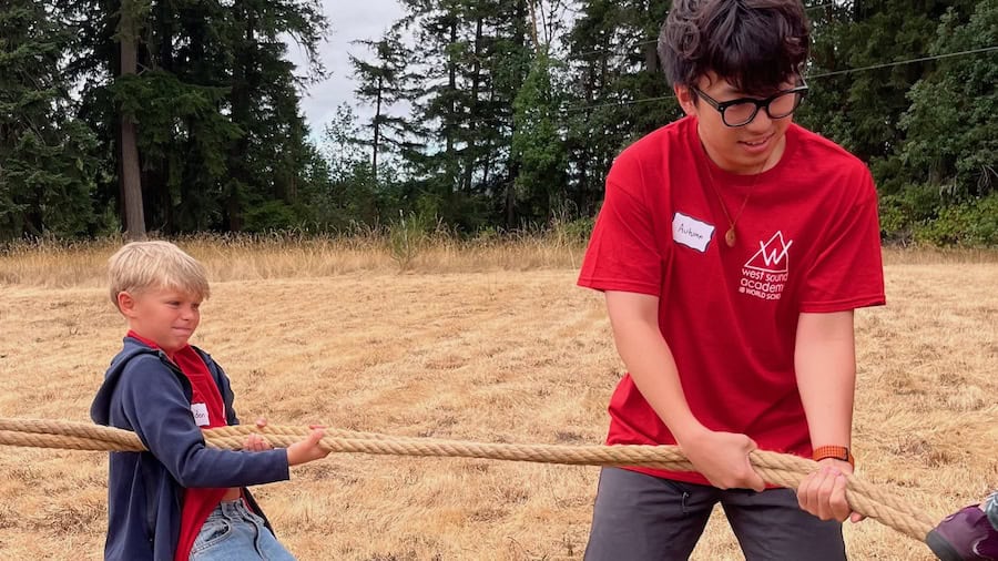 Two members of the red team, one in 6th grade and one in 12th, compete at Fall Gathering in tug-of-war