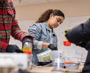 Student wearing gloves working with lab materials during a science class