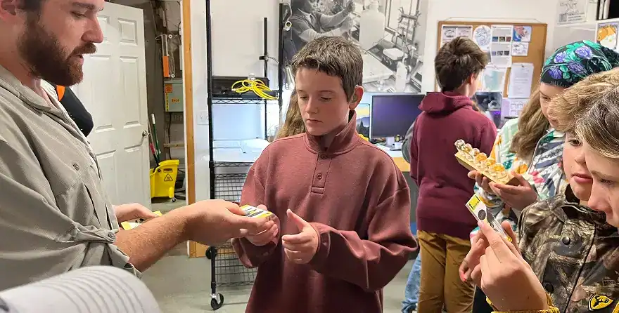 West Sound Academy Middle School Middle school students examining small specimens with an instructor in a classroom workshop